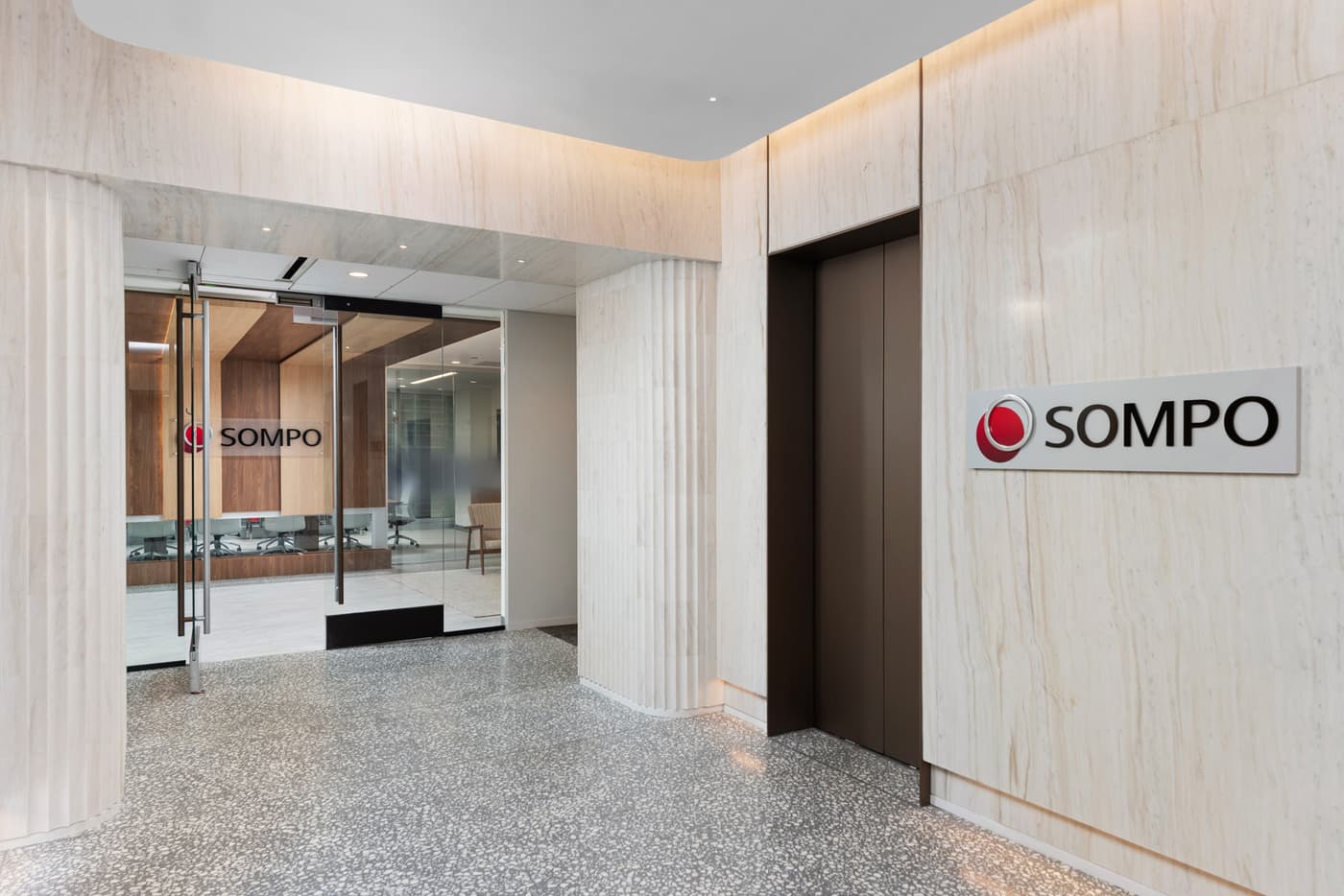 Sompo International's Miami office: reception lounge beneath a folded walnut ceiling with the Sompo wall sign, photograph 7