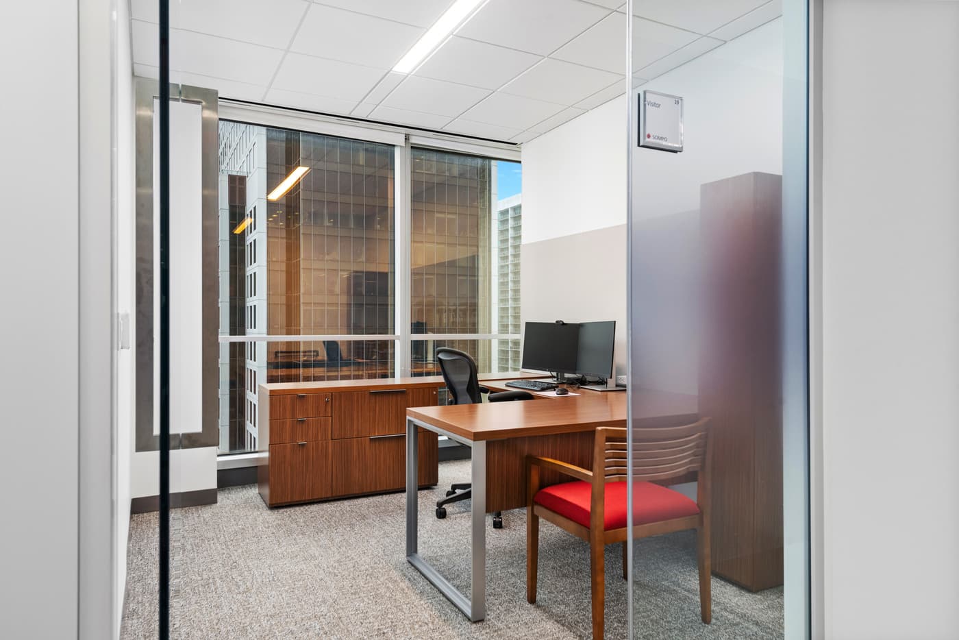Sompo International's Miami office: reception lounge beneath a folded walnut ceiling with the Sompo wall sign, photograph 9
