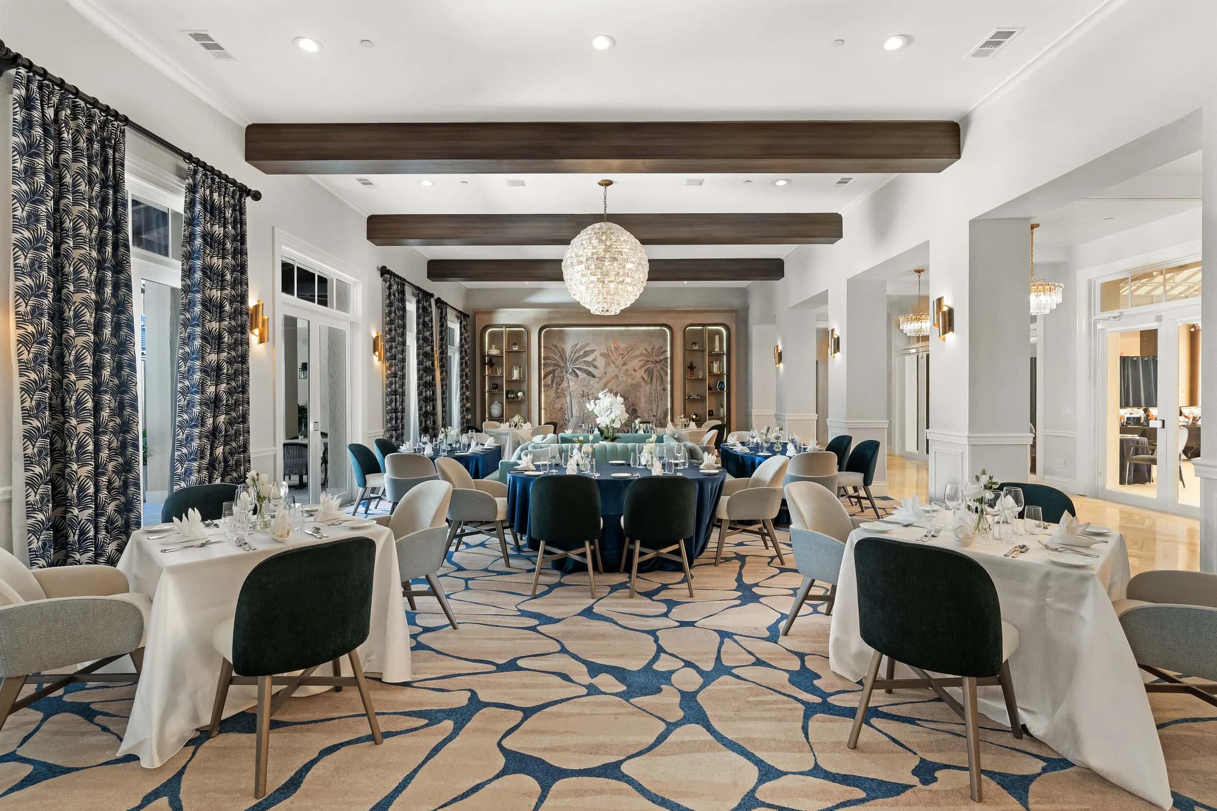 Deering Bay dining room set for dinner beneath a globe chandelier and timber beams