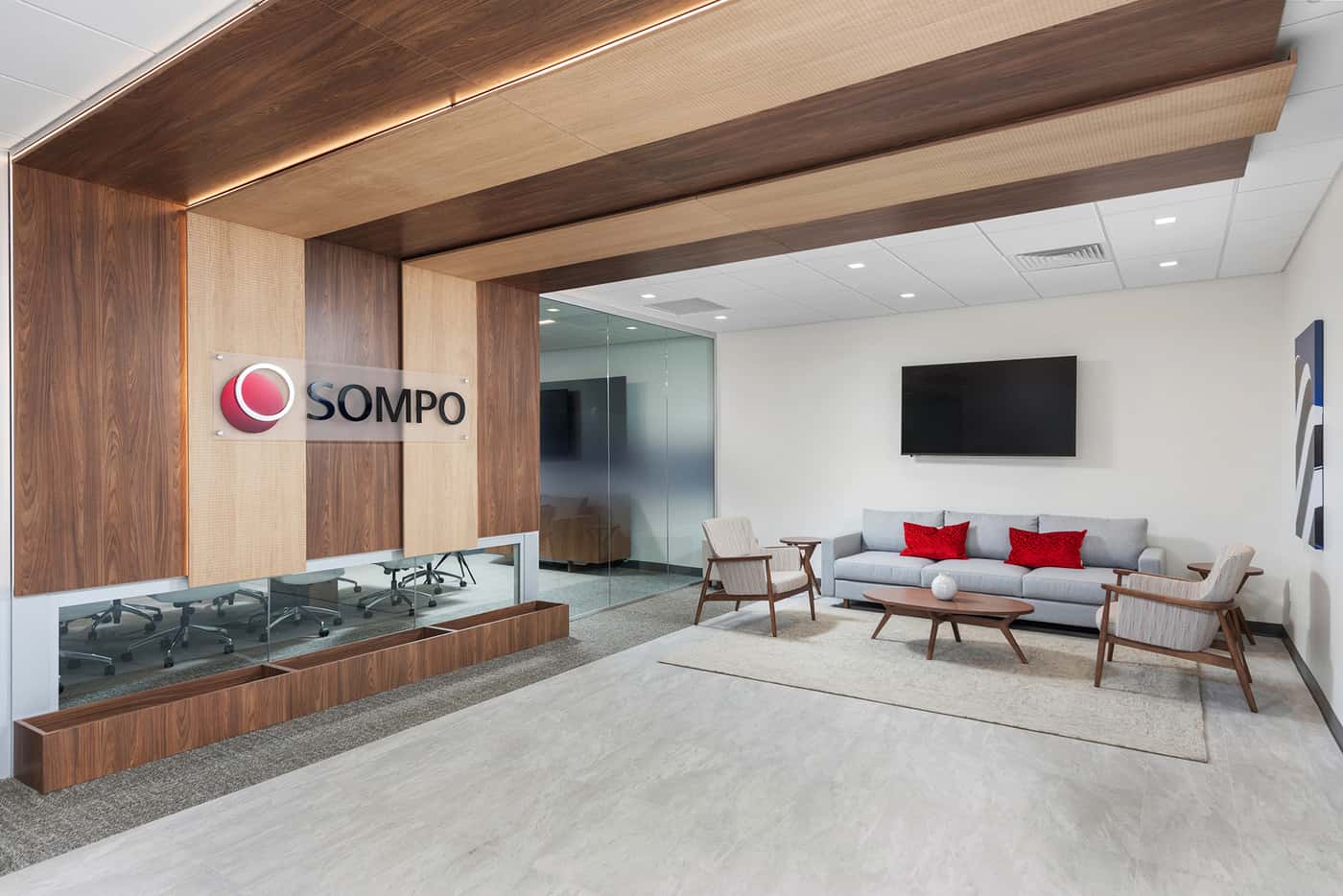 Sompo International's Miami office: reception lounge beneath a folded walnut ceiling with the Sompo wall sign